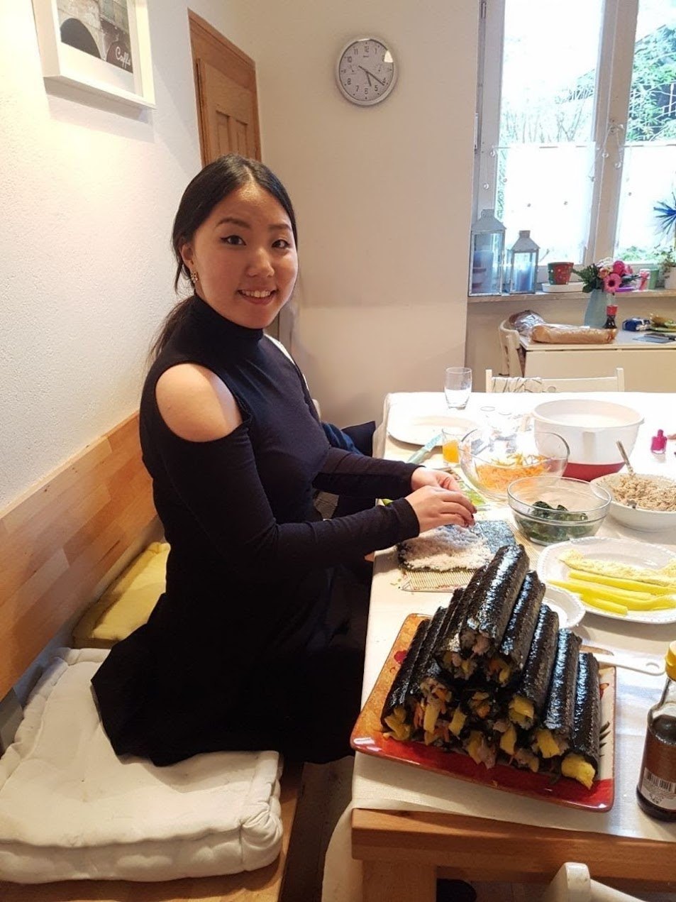 Sanni lächelt am Tisch, während sie einen Turm aus Gimbap macht